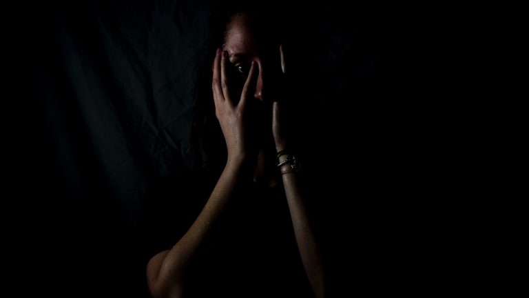 woman holding her face in dark room