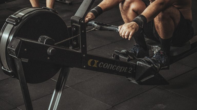 topless man using rowing machine